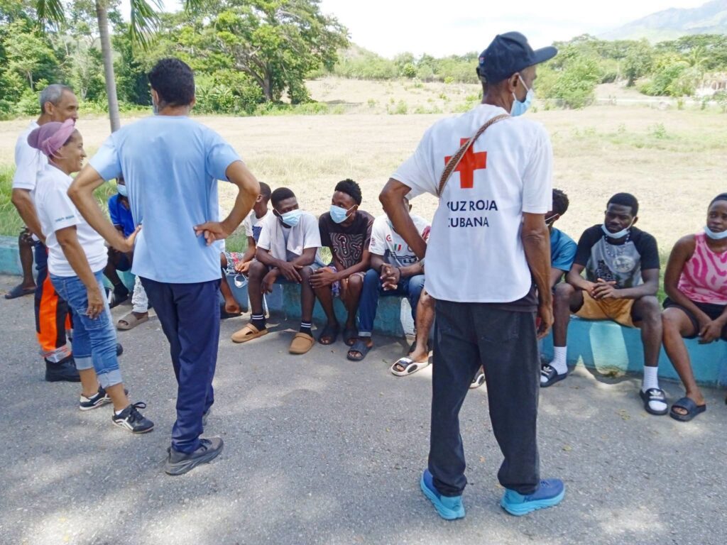 Personal de la Cruz Roja Cubana asistiendo a personas sentadas.