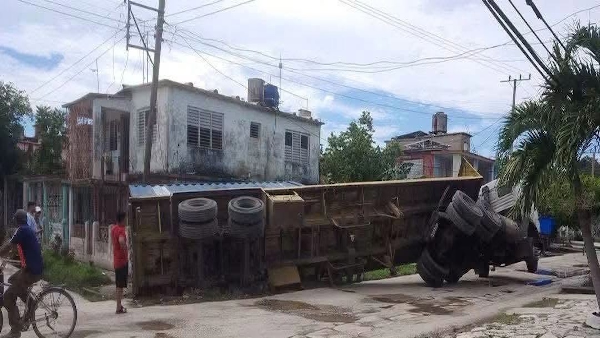Camión de carga volcado de costado en una calle residencial.