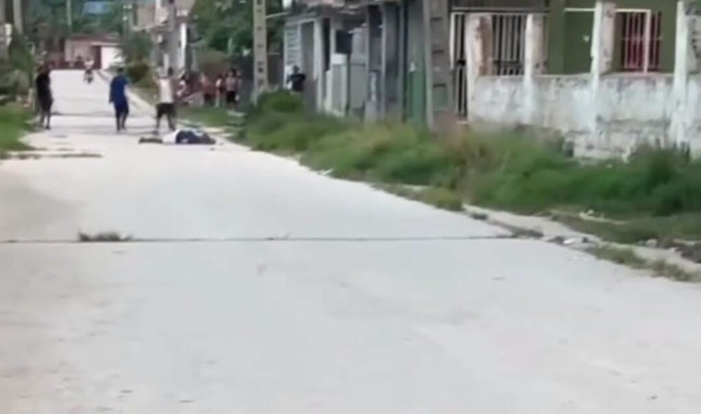 Persona tendida en el suelo en una calle con gente.