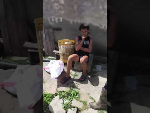 Joven sentado al aire libre junto a un cesto amarillo.