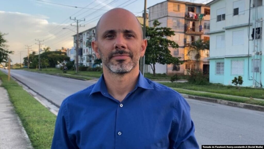 Hombre con camisa azul en una calle residencial urbana.