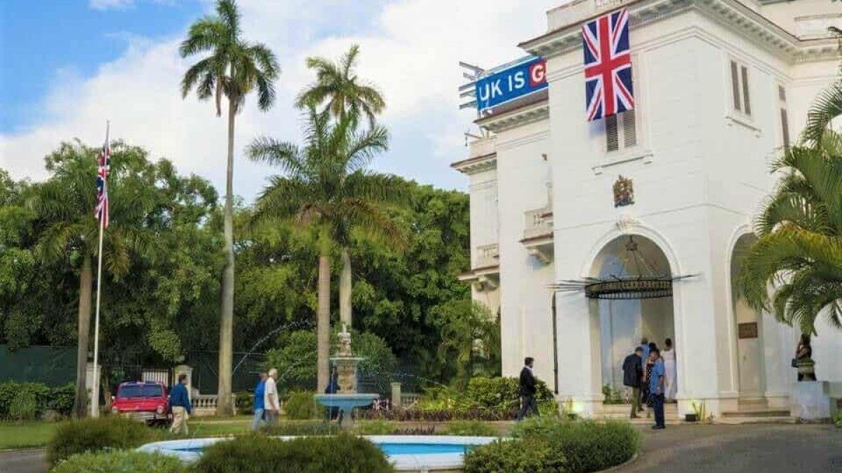 Edificio blanco colonial con bandera británica y palmeras.