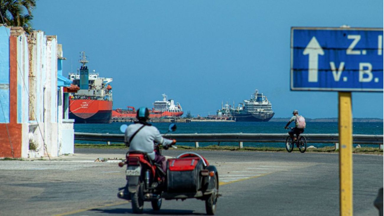 Motocicleta con sidecar frente a un puerto con barcos.