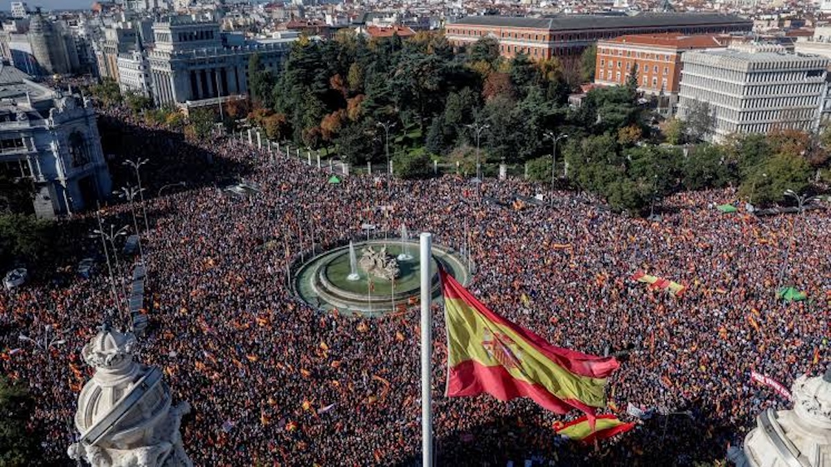 Multitud congregada en la Plaza de Cibeles con bandera española.