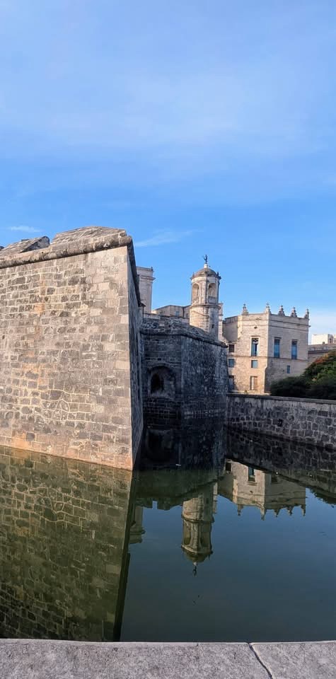 Fortaleza histórica de piedra con reflejo en el foso.