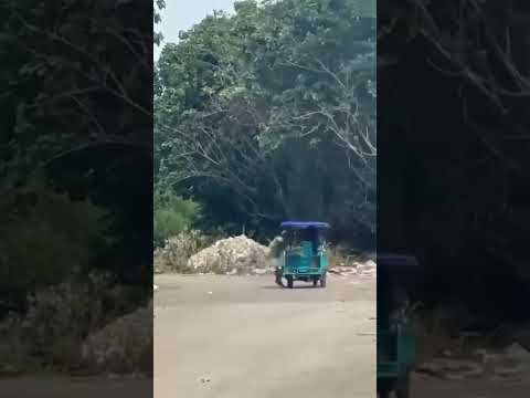 Mototaxi turquesa en una carretera rodeada de frondosa vegetación.