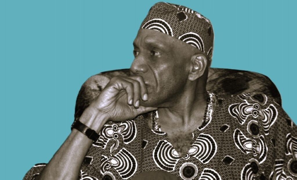 Retrato de Sun Ra con vestimenta tradicional y gesto pensativo.