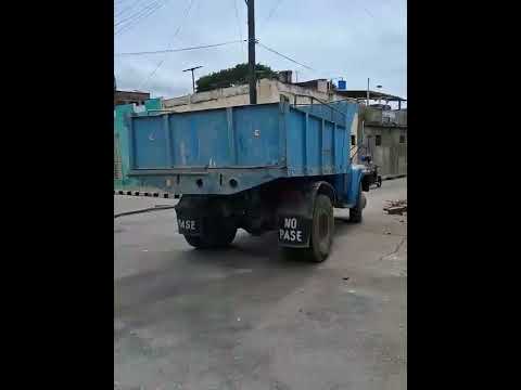 Camión de volteo azul antiguo en una calle urbana.