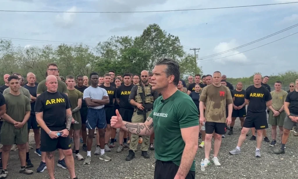 Hombre en camiseta de Marines hablando a soldados del ejército.