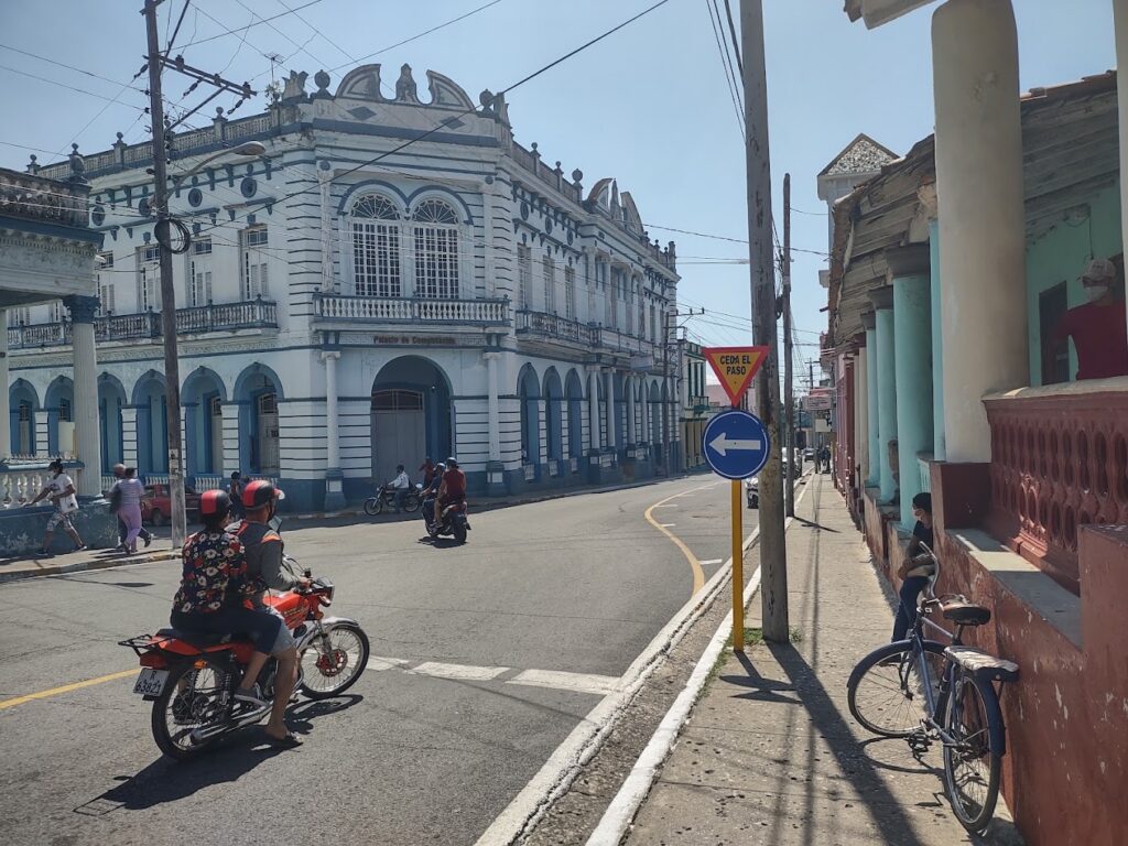 Calle con edificios coloniales y personas en motocicletas.